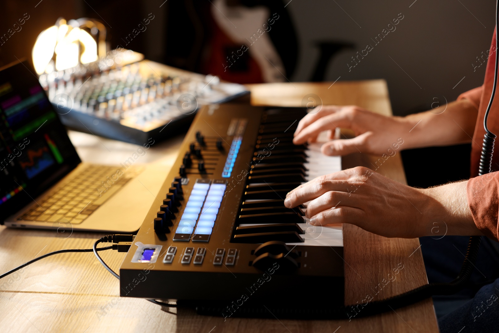 Man working with MIDI keyboard at wooden table indoors, closeup Photo of Man working with MIDI keyboard at wooden table indoors, closeup