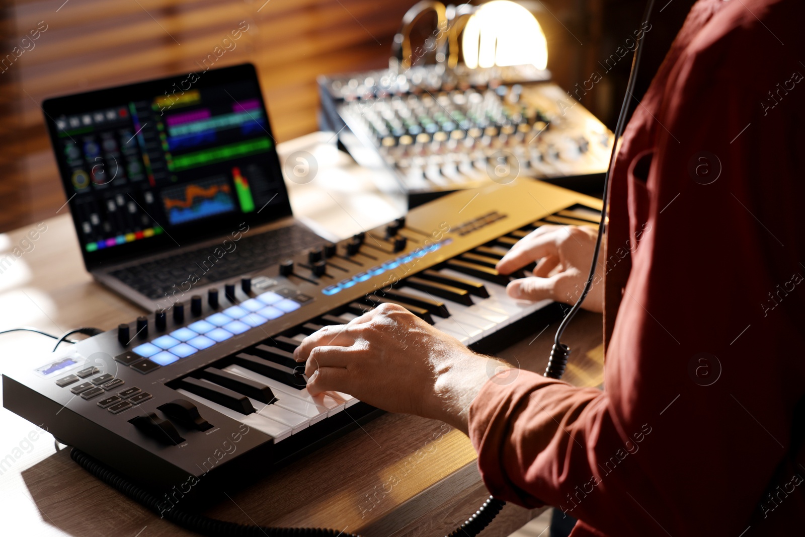 Man working with MIDI keyboard at wooden table indoors, closeup Photo of Man working with MIDI keyboard at wooden table indoors, closeup