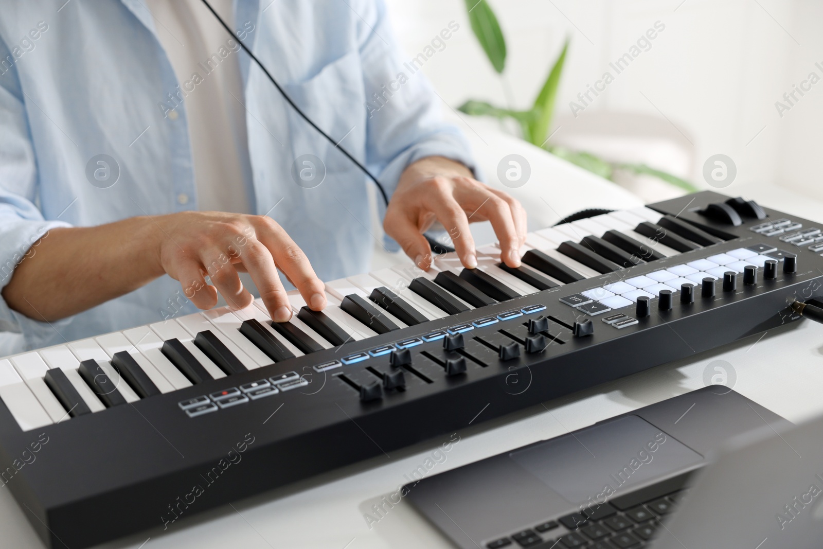 Man working with MIDI keyboard at white table indoors, closeup Photo of Man working with MIDI keyboard at white table indoors, closeup