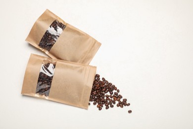 Photo of Zipper stand-up pouches and coffee beans on white table, flat lay. Mockup for design