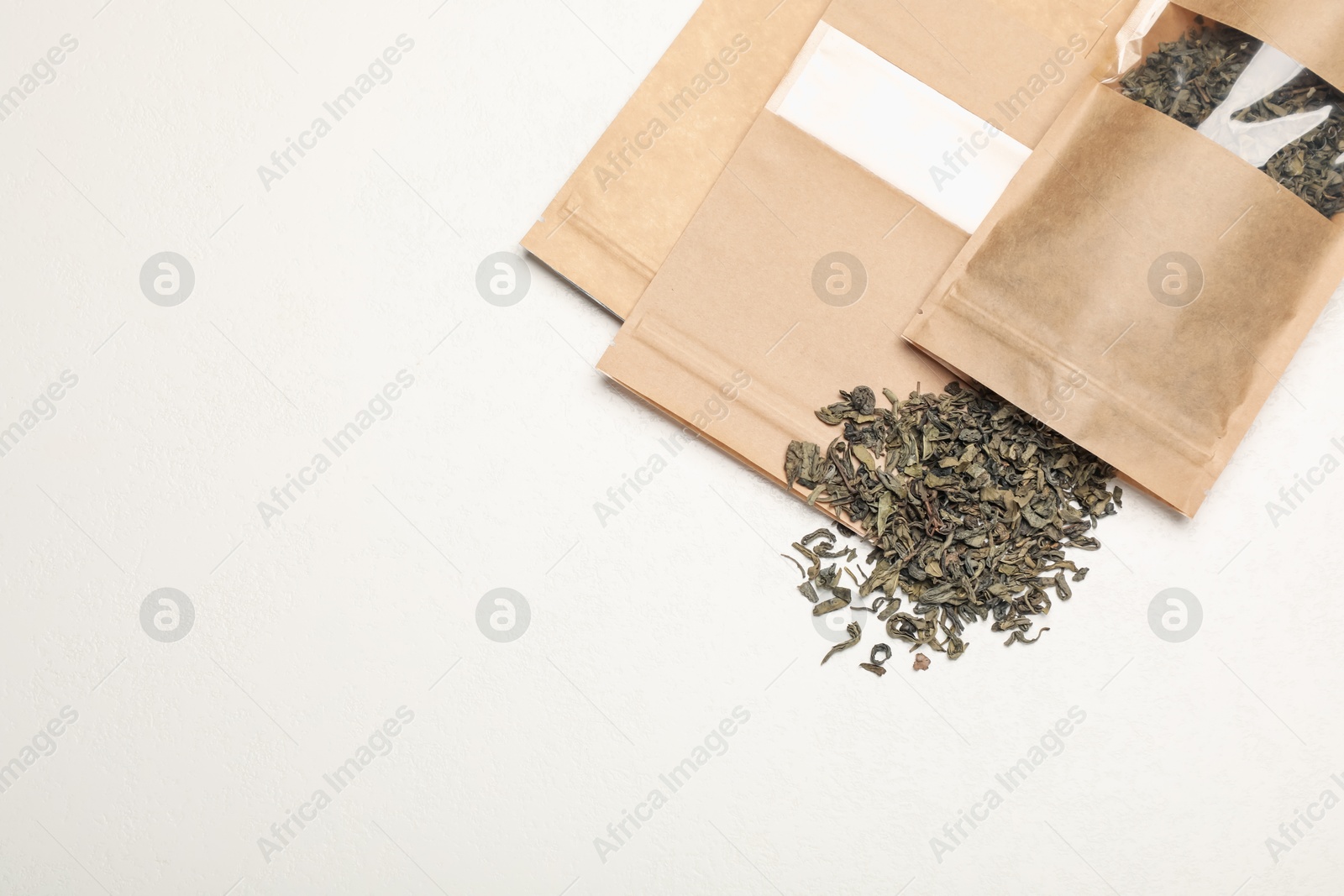 Zipper stand-up pouches and dry leaves on white table, flat lay. Mockup for design Photo of Zipper stand-up pouches and dry leaves on white table, flat lay. Mockup for design