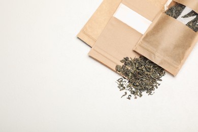 Photo of Zipper stand-up pouches and dry leaves on white table, flat lay. Mockup for design