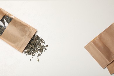 Photo of Zipper stand-up pouches and dry leaves on white table, flat lay. Mockup for design