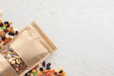 Photo of Zipper stand-up pouch with dried fruits and nuts on white wooden table, flat lay. Mockup for design