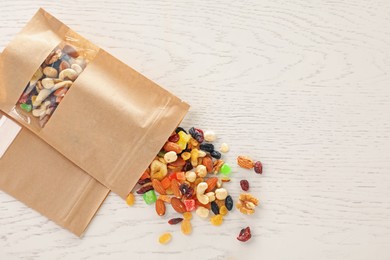 Photo of Zipper stand-up pouches with dried fruits and nuts on white wooden table, flat lay. Mockup for design