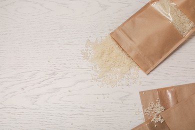 Photo of Zipper stand-up pouches with rice on white wooden table, flat lay. Mockup for design