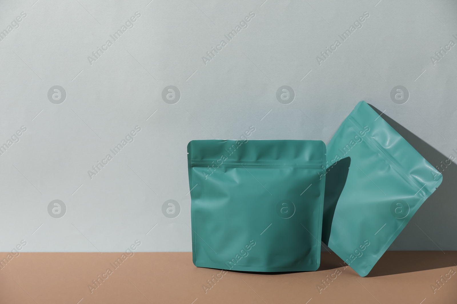 Zipper stand-up pouches on brown table against light grey background, mockup for design Photo of Zipper stand-up pouches on brown table against light grey background, mockup for design