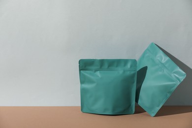 Photo of Zipper stand-up pouches on brown table against light grey background, mockup for design