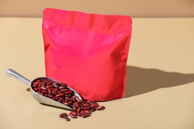 Photo of Zipper stand-up pouch and dry kidney beans on beige background, mockup for design