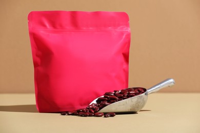 Photo of Zipper stand-up pouch and dry kidney beans on beige background, closeup. Mockup for design