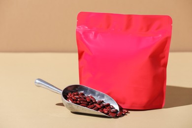 Photo of Zipper stand-up pouch and dry kidney beans on beige background, closeup. Mockup for design