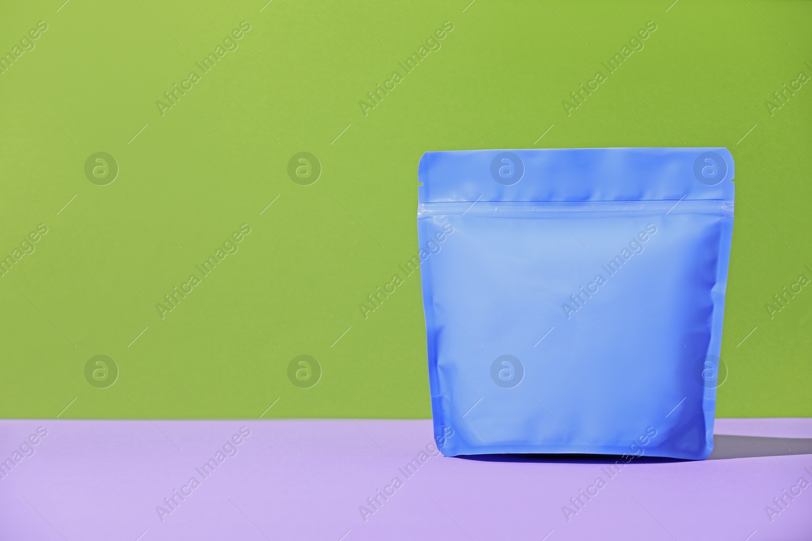 Zipper stand-up pouch on violet table against green background. Mockup for design Photo of Zipper stand-up pouch on violet table against green background. Mockup for design
