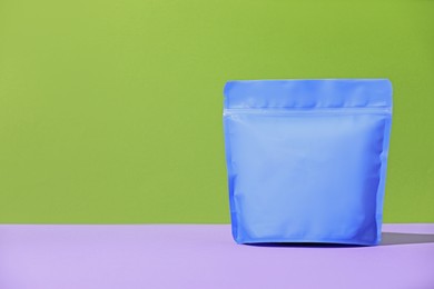 Photo of Zipper stand-up pouch on violet table against green background. Mockup for design