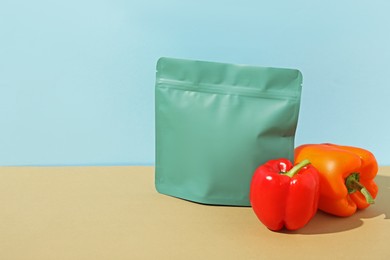 Photo of Zipper stand-up pouch and bell peppers on beige table against light blue background. Mockup for design
