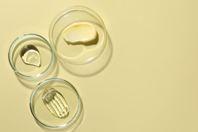 Photo of Different cosmetic products in Petri dishes on pale yellow background, flat lay. Space for text