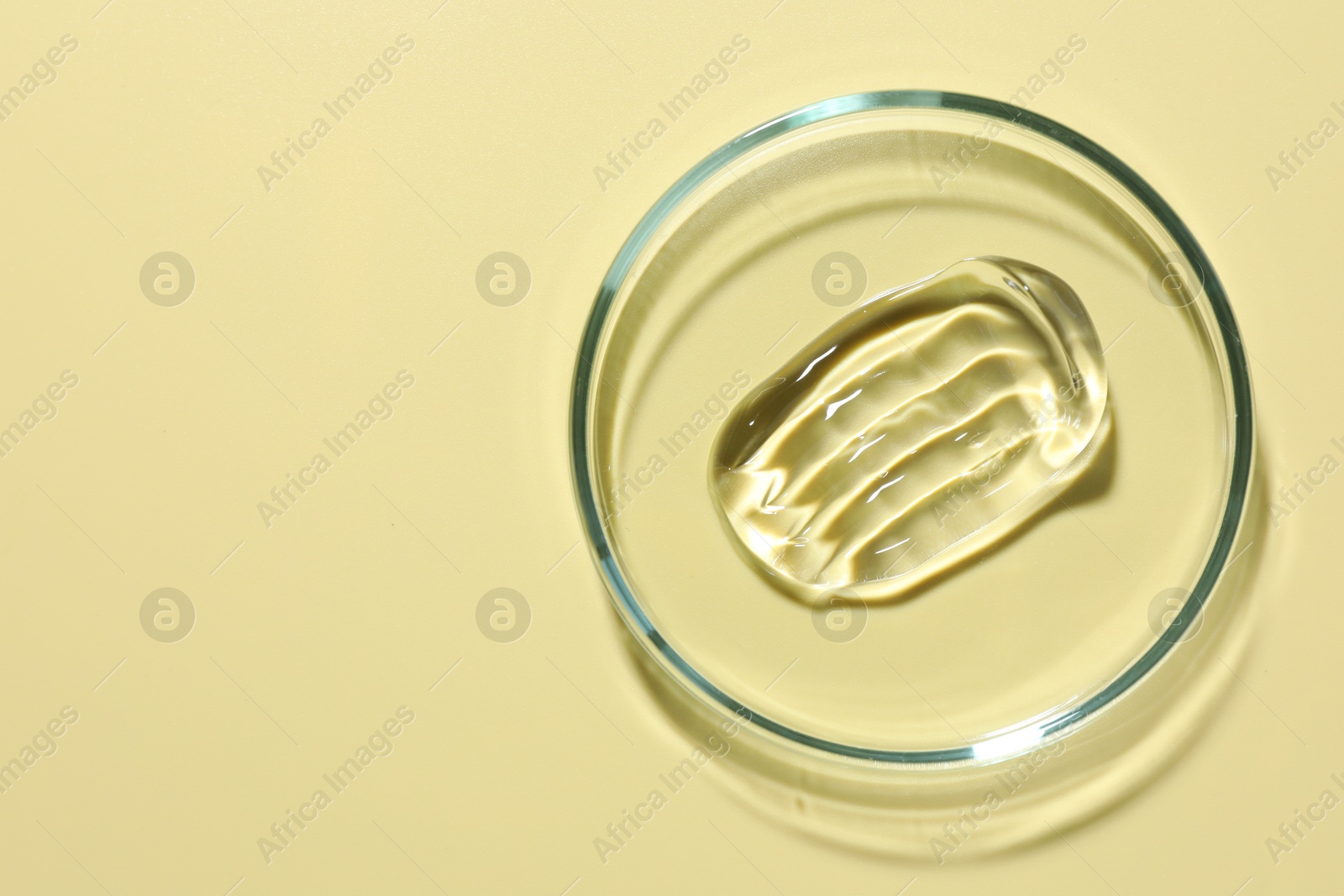 Cosmetic product in Petri dish on pale yellow background, top view. Space for text Photo of Cosmetic product in Petri dish on pale yellow background, top view. Space for text