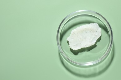 Photo of Cosmetic product in Petri dish on green background, top view. Space for text