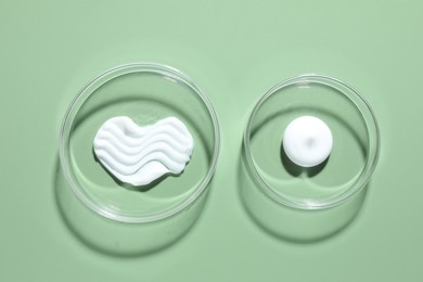 Photo of Different cosmetic products in Petri dishes on green background, flat lay