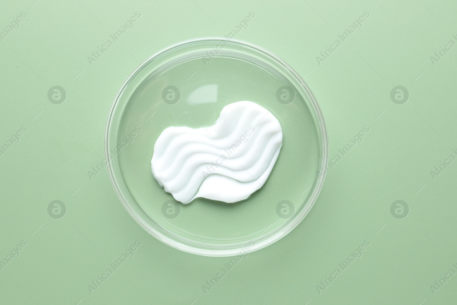 Cosmetic product in Petri dish on green background, top view Photo of Cosmetic product in Petri dish on green background, top view
