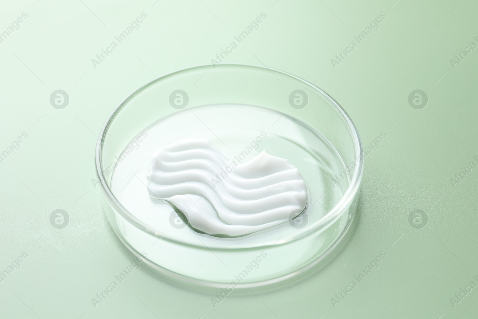 Cosmetic product in Petri dish on green background, closeup Photo of Cosmetic product in Petri dish on green background, closeup