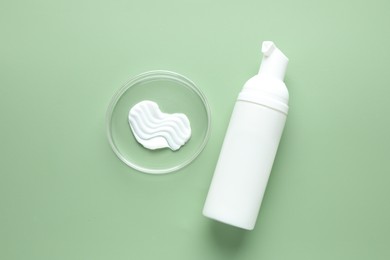 Photo of Cosmetic product in Petri dish and bottle on green background, flat lay