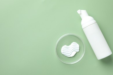 Photo of Cosmetic product in Petri dish and bottle on green background, flat lay. Space for text