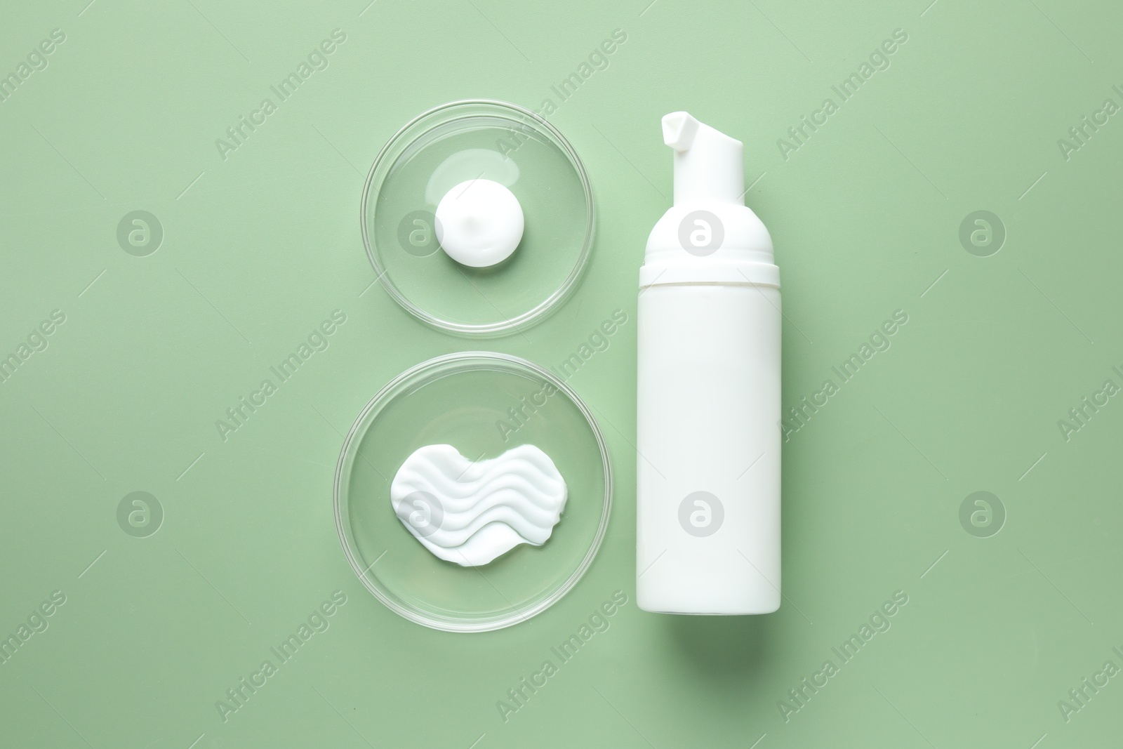 Different cosmetic products in Petri dishes and bottle on green background, flat lay Photo of Different cosmetic products in Petri dishes and bottle on green background, flat lay