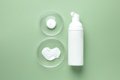 Photo of Different cosmetic products in Petri dishes and bottle on green background, flat lay