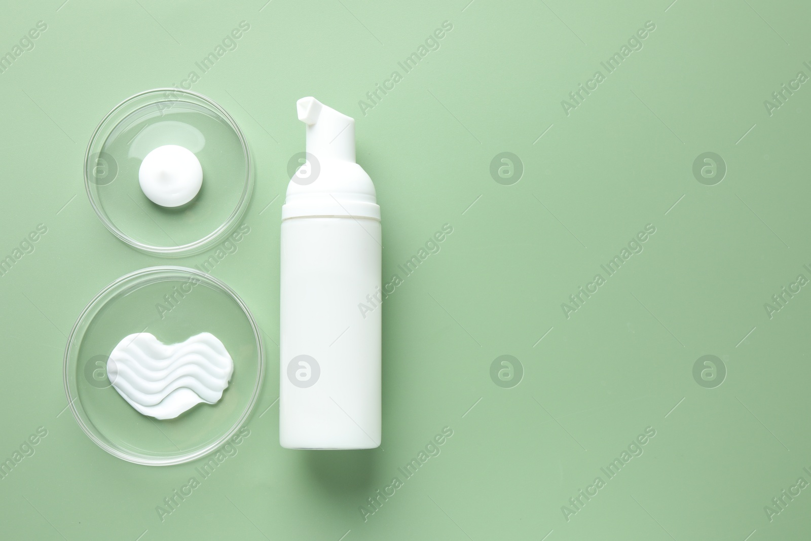 Different cosmetic products in Petri dishes and bottle on green background, flat lay. Space for text Photo of Different cosmetic products in Petri dishes and bottle on green background, flat lay. Space for text