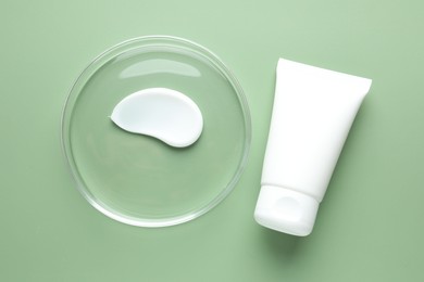 Photo of Cosmetic product in Petri dish and tube on green background, flat lay