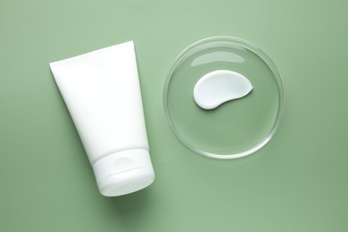 Photo of Cosmetic product in Petri dish and tube on green background, flat lay
