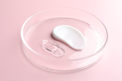 Photo of Different cosmetic products in Petri dish on pink background, closeup