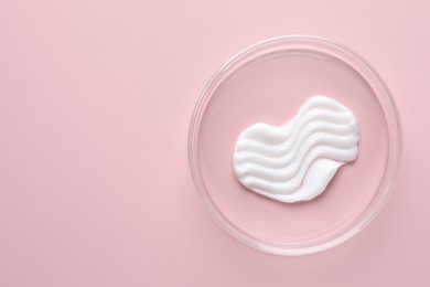 Photo of Cosmetic product in Petri dish on pink background, top view. Space for text