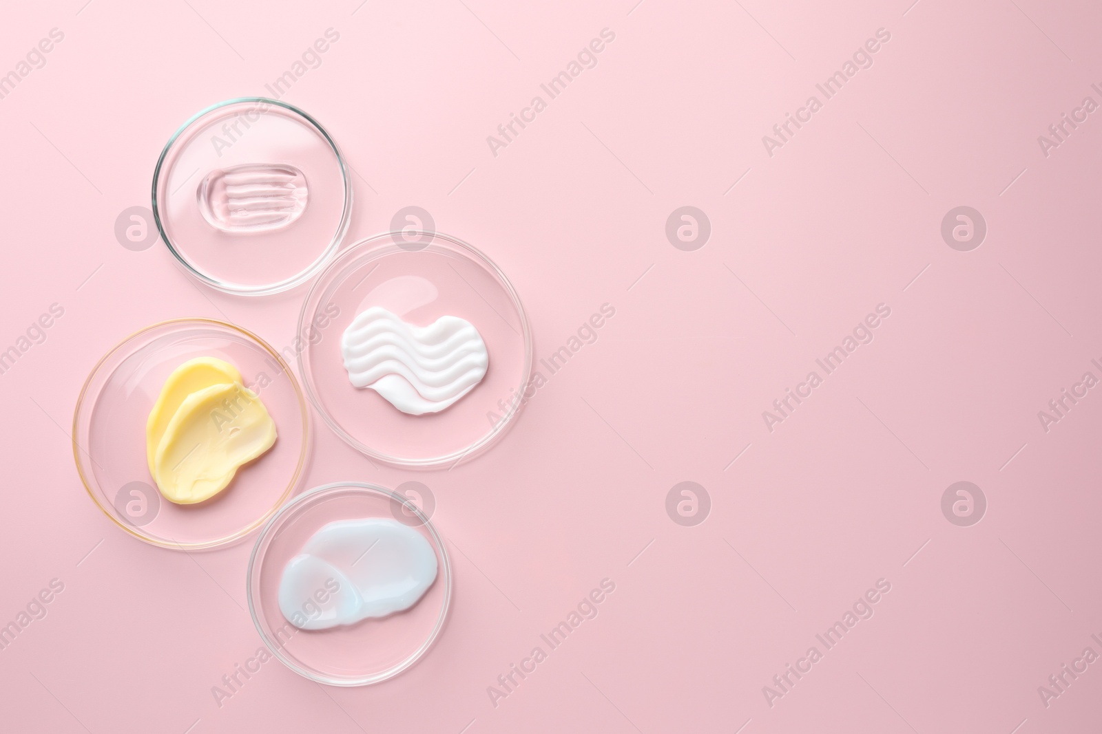 Different cosmetic products in Petri dishes on pink background, flat lay. Space for text Photo of Different cosmetic products in Petri dishes on pink background, flat lay. Space for text