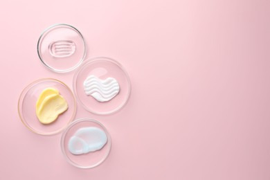 Photo of Different cosmetic products in Petri dishes on pink background, flat lay. Space for text