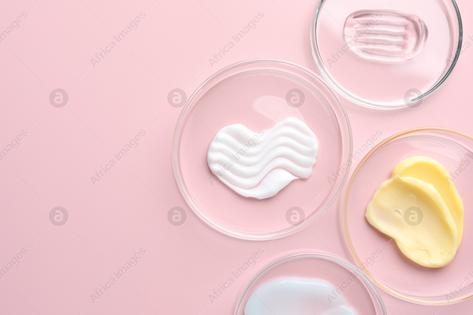 Different cosmetic products in Petri dishes on pink background, flat lay. Space for text Photo of Different cosmetic products in Petri dishes on pink background, flat lay. Space for text