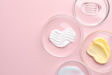Photo of Different cosmetic products in Petri dishes on pink background, flat lay. Space for text
