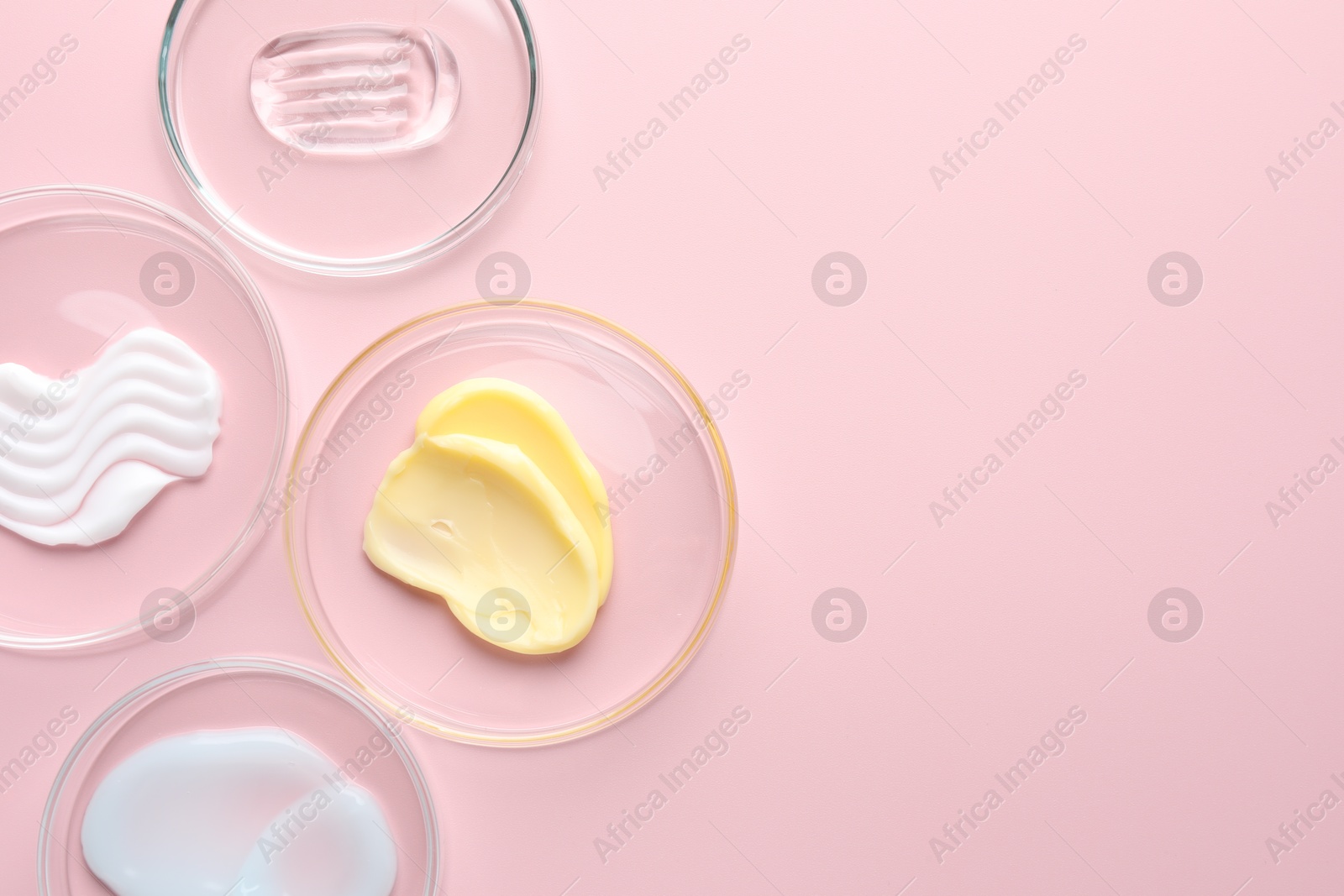 Different cosmetic products in Petri dishes on pink background, flat lay. Space for text Photo of Different cosmetic products in Petri dishes on pink background, flat lay. Space for text