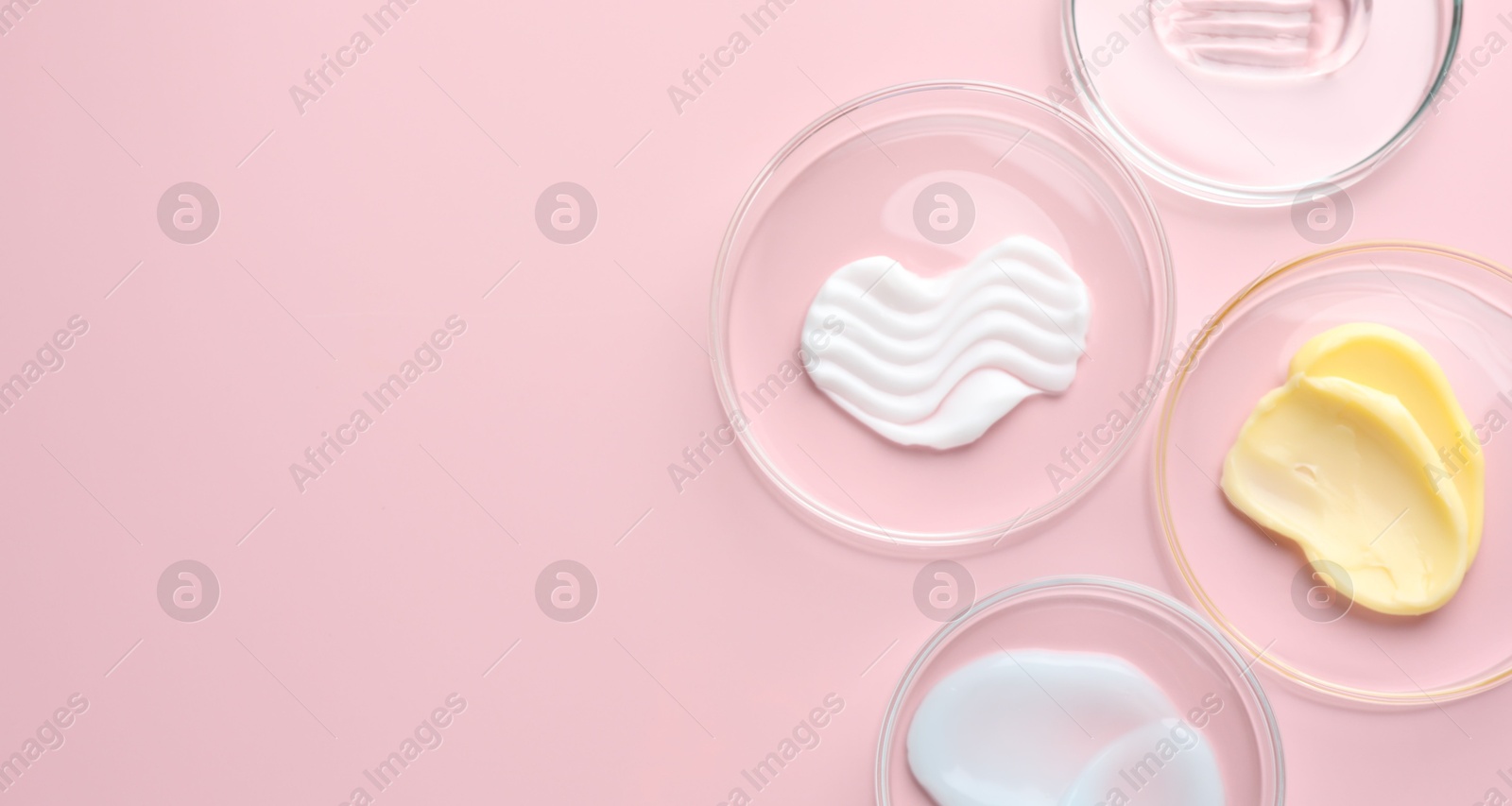 Different cosmetic products in Petri dishes on pink background, flat lay. Space for text Photo of Different cosmetic products in Petri dishes on pink background, flat lay. Space for text