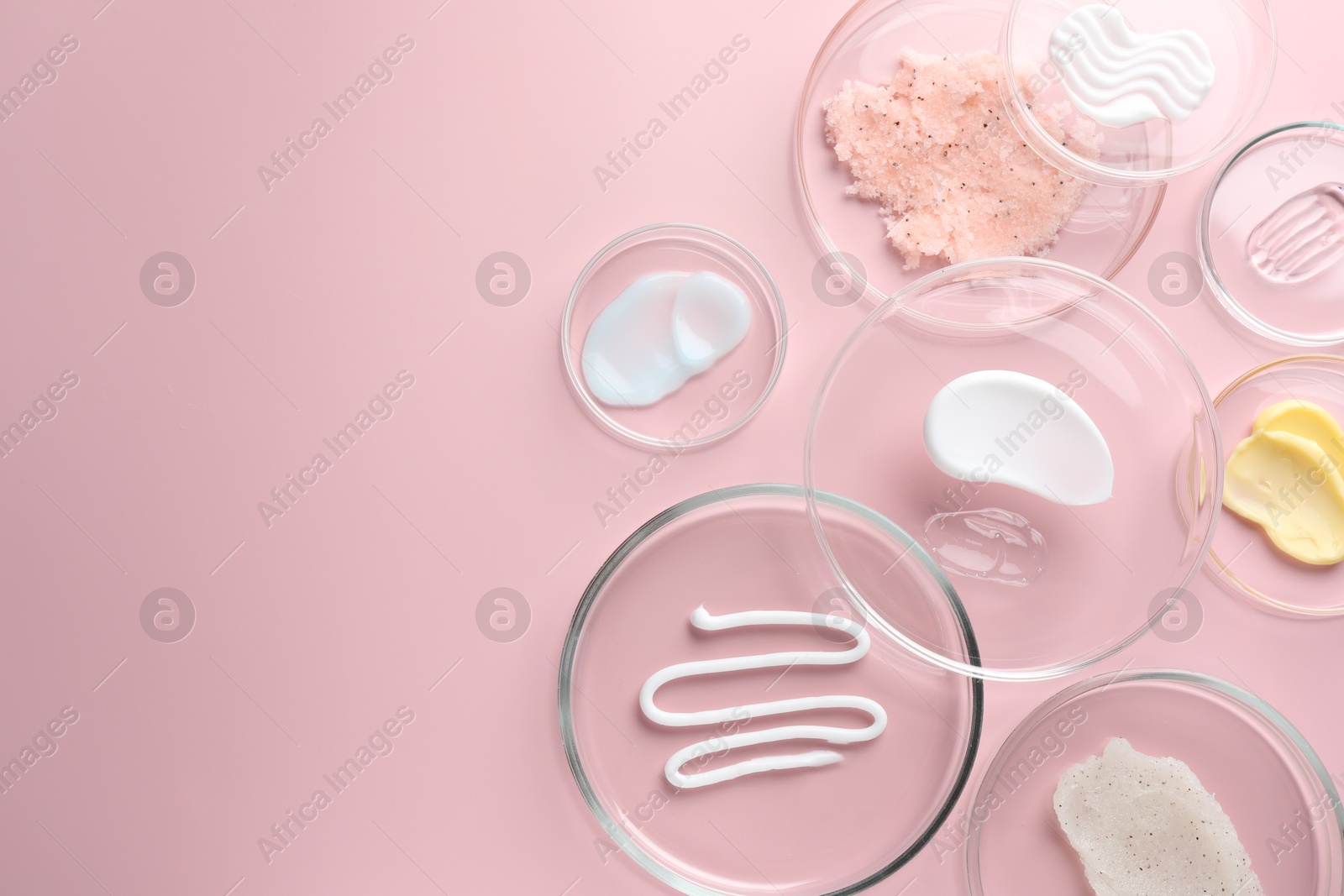 Different cosmetic products in Petri dishes on pink background, flat lay. Space for text Photo of Different cosmetic products in Petri dishes on pink background, flat lay. Space for text
