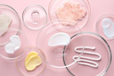 Photo of Different cosmetic products in Petri dishes on pink background, flat lay