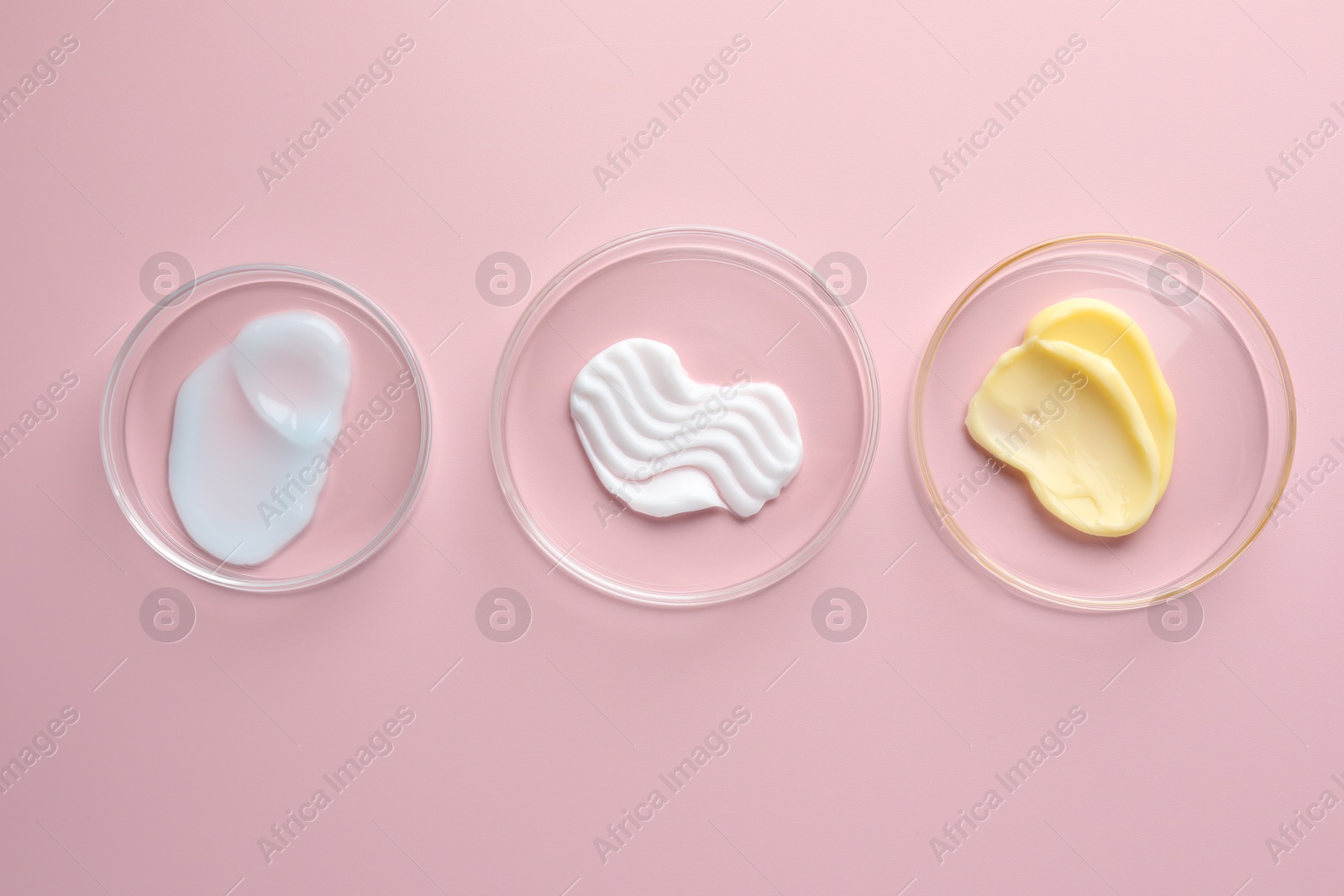 Different cosmetic products in Petri dishes on pink background, flat lay Photo of Different cosmetic products in Petri dishes on pink background, flat lay