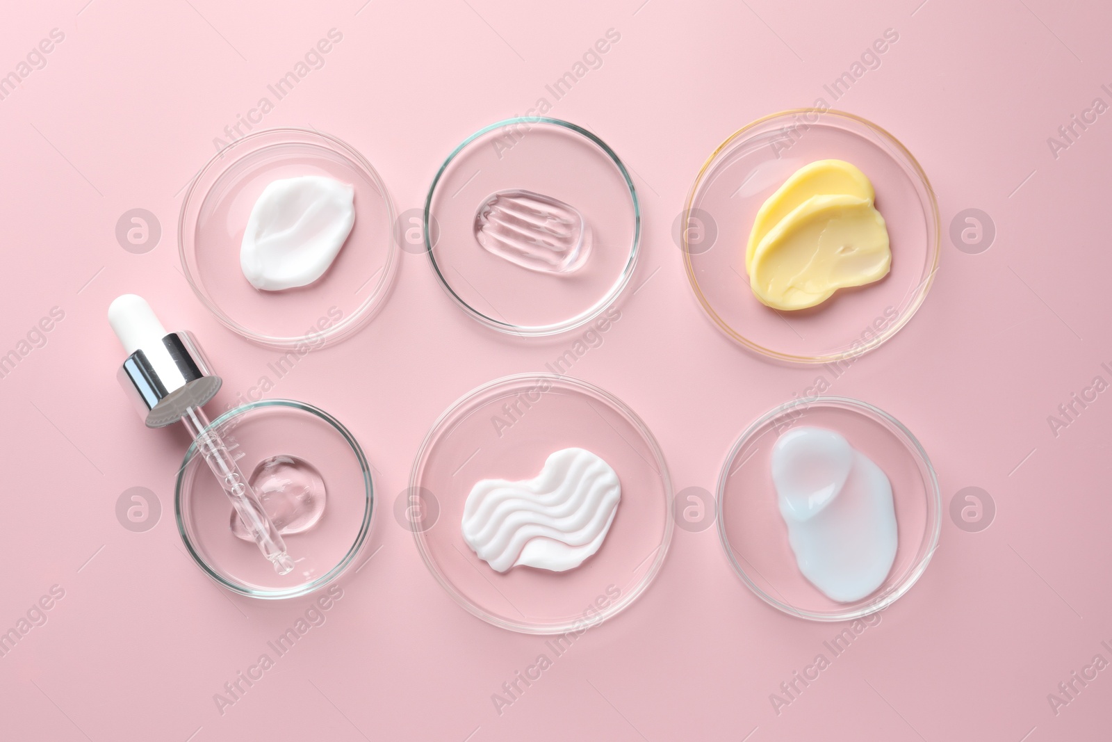 Different cosmetic products in Petri dishes and dropper on pink background, flat lay Photo of Different cosmetic products in Petri dishes and dropper on pink background, flat lay