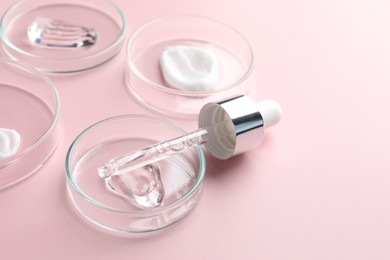 Photo of Different cosmetic products in Petri dishes and dropper on pink background, closeup. Space for text