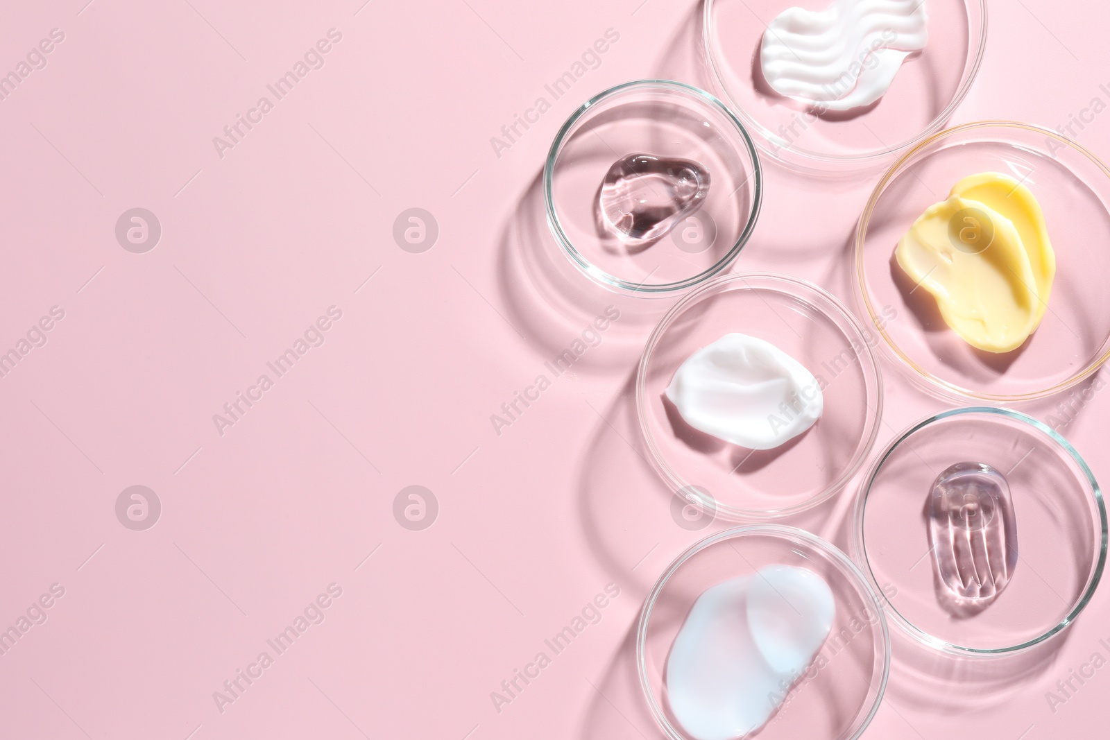 Different cosmetic products in Petri dishes on pink background, flat lay. Space for text Photo of Different cosmetic products in Petri dishes on pink background, flat lay. Space for text