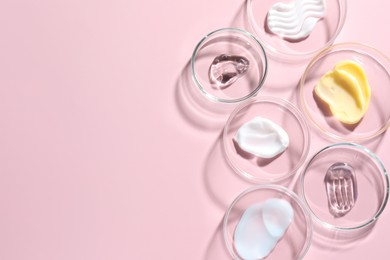 Photo of Different cosmetic products in Petri dishes on pink background, flat lay. Space for text
