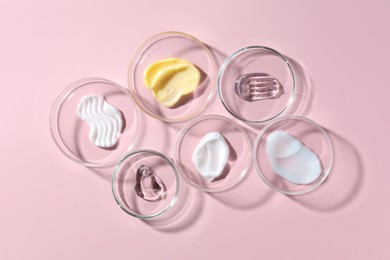 Photo of Different cosmetic products in Petri dishes on pink background, flat lay