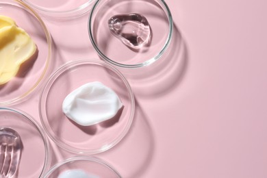 Photo of Different cosmetic products in Petri dishes on pink background, flat lay. Space for text