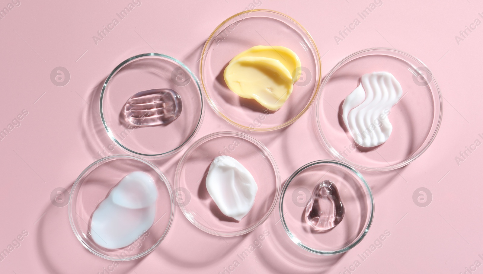 Different cosmetic products in Petri dishes on pink background, flat lay Photo of Different cosmetic products in Petri dishes on pink background, flat lay