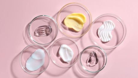Photo of Different cosmetic products in Petri dishes on pink background, flat lay